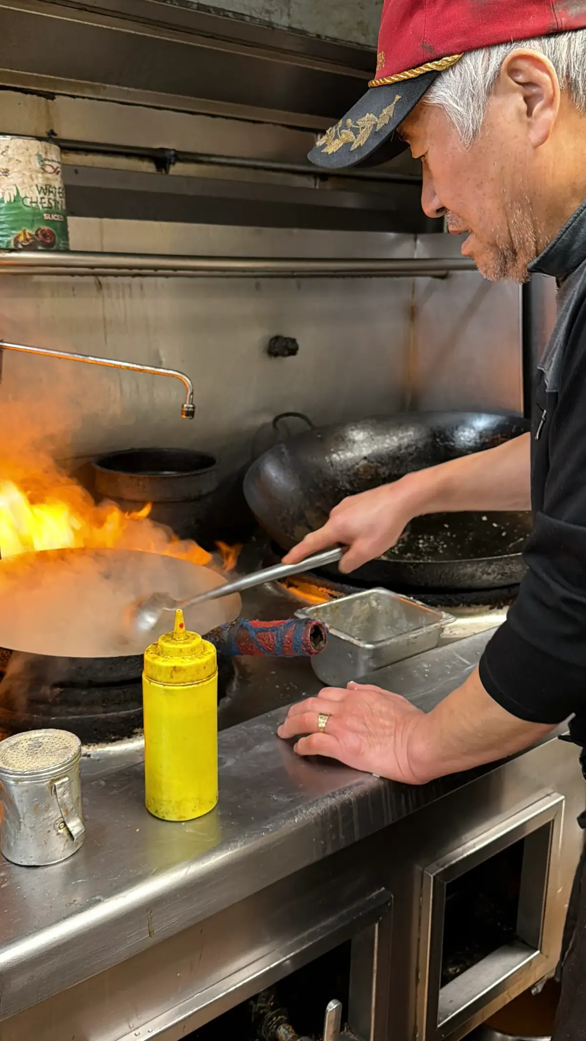 Mr. Kim cooking at the wok over open flames in the Sam and Lee's kitchen